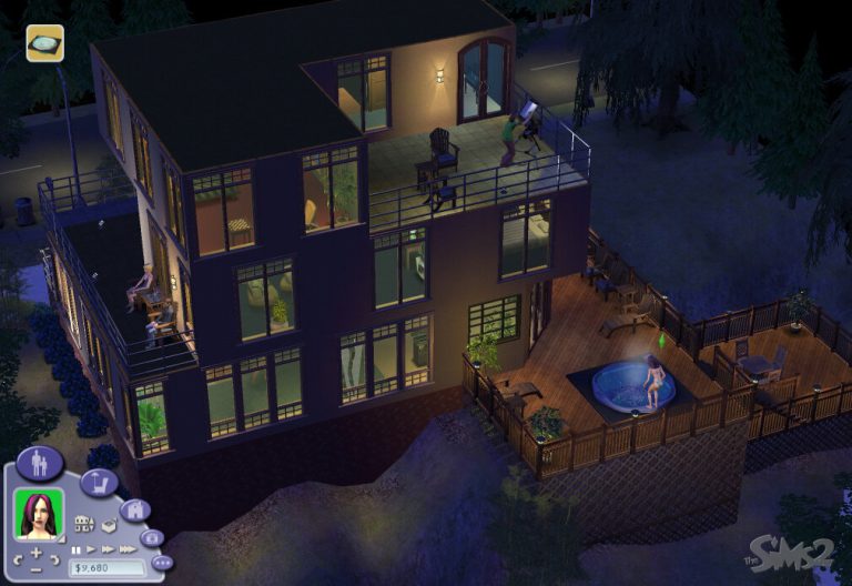 Screenshot of The Sims 2 displaying an isometric nighttime view of a large, modern three-story house built on a hillside. The house features dark exterior walls, extensive glass windows illuminating the furnished interior, a top-floor balcony where a Sim is looking through a telescope, and a spacious wooden deck with a glowing blue hot tub where a female Sim is relaxing. The classic Sims 2 user interface is visible in the bottom left corner, showing a female Sim's portrait and the household funds.