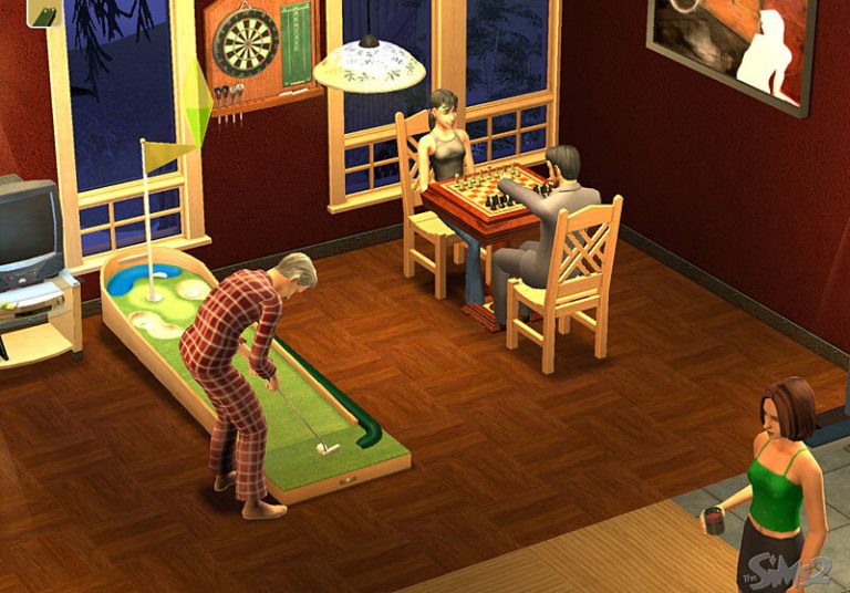 Screenshot of The Sims 2 showing a recreation room at night. One Sim in plaid pajamas is practicing on an indoor mini-golf putting green. Two Sims are sitting at a small table playing chess near a window. A fourth Sim in a green top stands nearby holding a red cup. The room features wood floors, a dartboard on the wall, and a television.