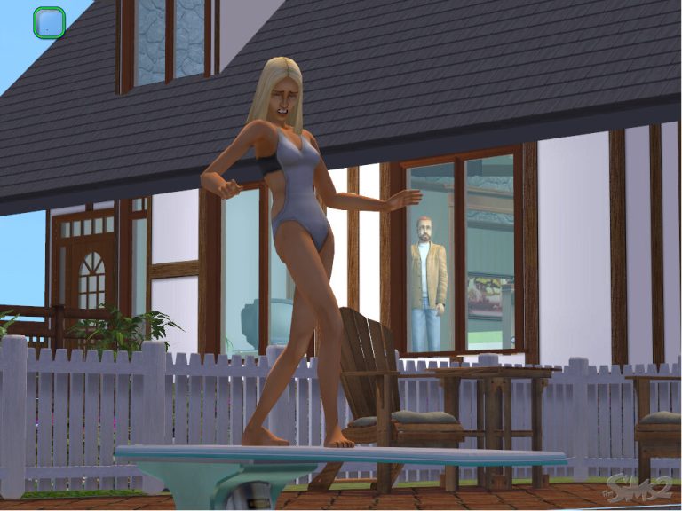 Screenshot of The Sims 2 showing a Sim standing on the edge of a light blue diving board. The Sim has blonde hair, is wearing a white and black swimsuit, and appears nervous or unsteady with their arms extended. In the background, another Sim is watching them from inside a house through a large glass window. A white picket fence and patio furniture are also visible.