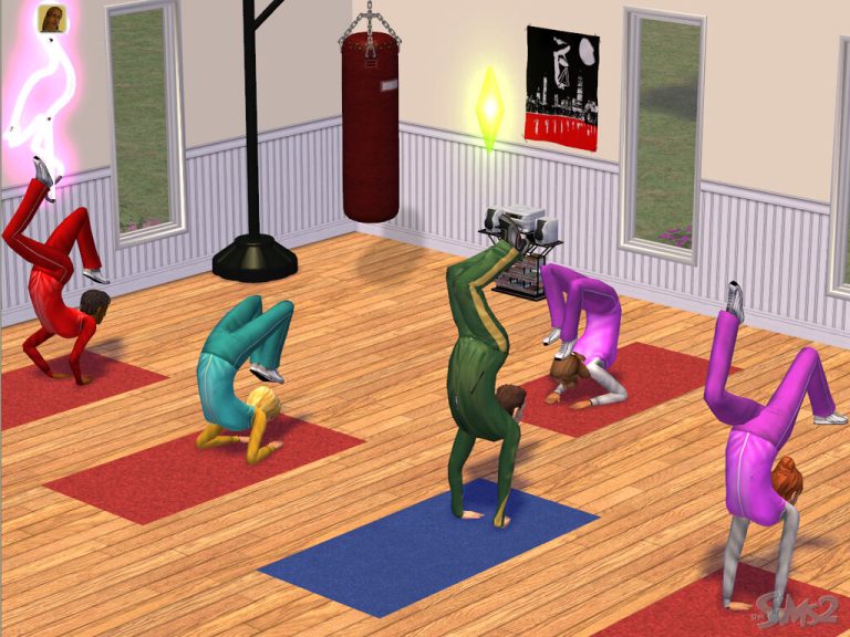 Screenshot of The Sims 2 showing an indoor gym room with wooden floors and large mirrors. Five Sims wearing colorful tracksuits in red, teal, dark green, pink, and purple are performing a yoga headstand pose on red and blue exercise mats. A red punching bag and a framed poster are visible in the background, and a green Plumbob floats above the Sim in the center.